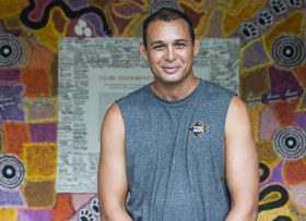 Thomas Mayo in front of an indigenous art